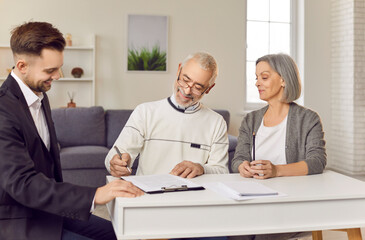 Couple of a senior clients signing a contract with a real estate agent or financial adviser at...