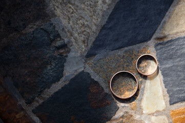 Pair of Golden Wedding Rings on Textured Stone Surface..
