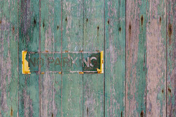 Remains of an old no parking sign on a old timber wall with green pealing paint