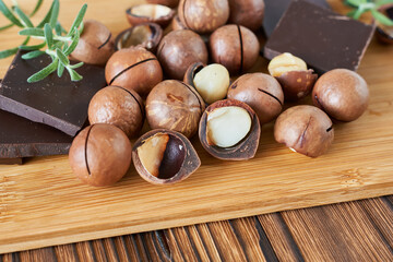 Macadamia nuts with chocolate and rosemary on a wooden background
