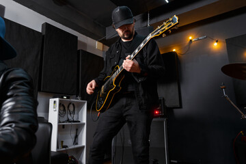 Musician Playing Electric Guitar in Black Studio Interior with Ambient Lighting..