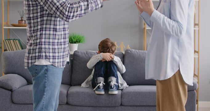 Sad child crying sitting at sofa while witnessing a quarrel between parents at home. Arguments and violence, highlighting the stress, conflict, and impact on the child, including divorce. - Powered by Adobe