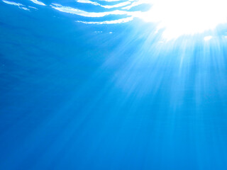Ocean blue underwater with sunrays, Underwater Sea Deep Water Abstract Sunshine, sea wave , clean waters in summer time, Natural underwater seascape, sand on ocean floor and water surface with sunligh