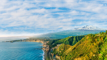scenic view from above to a beautiful coast with mediterranean touristic town with sea gulf and wonderful coastline and blue cloudy sky on background