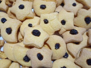 Full frame shot of cookies. 
These are golden yellow butter cookies, shaped like stars and circles, with a raisin in the center of each.