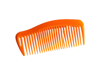 Bright orange plastic comb resting on a smooth white surface during early morning light isolated on transparent background