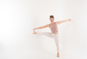 Athletic woman performing yoga exercise on white studio background.