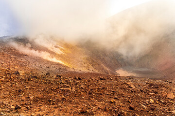 Aerial landscape view of volcano crater with smoke coming. An active erupting volcano with...