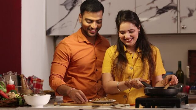 Husband and wife are both cooking together in the kitchen