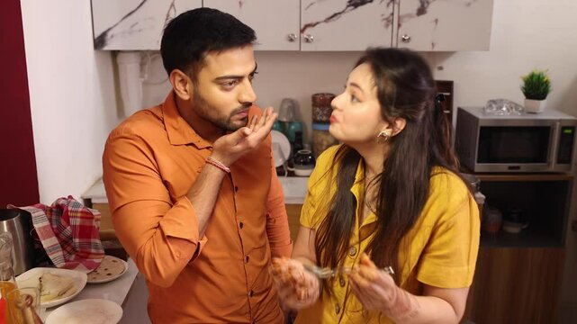 husband wiping kitchen table with kitchen cloth at home while his wife helping him in the kitchen