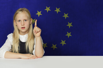 Curious young child girl pointing up on flag of European Union background. Education in EU concept