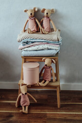 Adorable handmade fabric mice dolls dressed in pink sitting on a wooden stool with folded pastel...