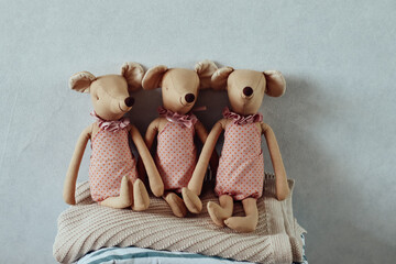 Adorable handmade fabric mice dolls dressed in pink sitting on a wooden stool with folded pastel blankets. Perfect for cozy nursery decor, children's room styling, or unique handmade gifts.