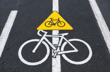 Bike path sign on asphalt: Painted symbol, road marking, cycle lane. Guidance for cyclists and traffic.