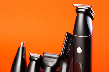 Modern set of hair trimmer with different attachments on a red background, close-up. Copy space for...