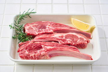 白いバットに並べた生のラムチョップ肉
