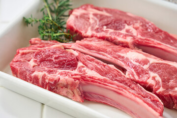 白いバットに並べた生のラムチョップ肉