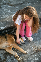 Girl petting a stray dog outdoor .Kid and dog