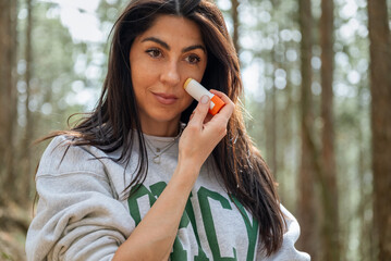 Woman applying sunscreen stick  in the spring mountain .Spf stick 