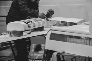 Painter paints the air conditioner housing from a paint sprayer in the workshop, painter, painting