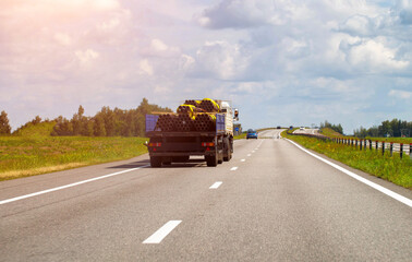 Transporting metal pipes on a semi-trailer truck along a highway in summer, industry....