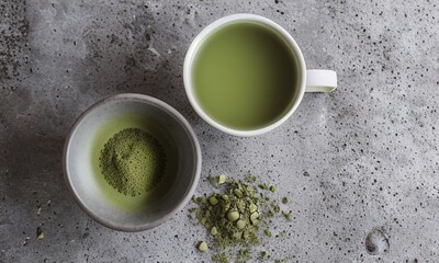 Top view of a white cup filled with vibrant matcha green tea, placed on a wooden surface beside a bowl of matcha powder.