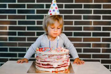 Little boy with birthday hat blowing candles