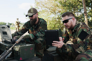 Army troops in camouflage and helmets prepare for combat at the training ground, entering data into...