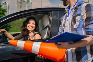 Male instructor holding traffic cone and test report while standing near car. Happy lady studying...
