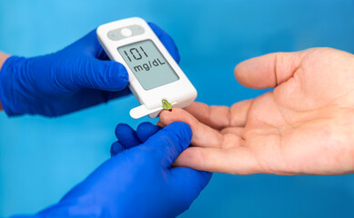 Blood glucose meter measures levels during a health check in a clinical setting with healthcare...