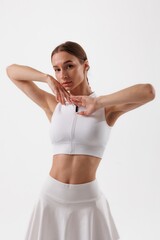 Model poses gracefully in white athletic attire against a clean backdrop showcasing elegance and...