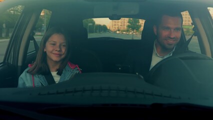 Close up of happy Caucasian man driving car with little girl in front seat. Cheerful young handsome...