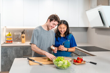 Young couple preparing healthy salad in modern kitchen