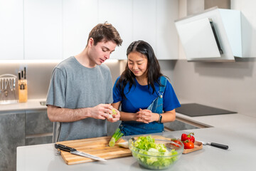 Young couple preparing vegetables for a fresh salad in modern kitchen