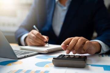 Business finance and budget management, Businessman using calculator and analyzing invoices and tax documents to manage company finances, Budget, Monthly expenses on desk with documents and reports.