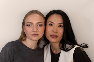 A professional makeup artist and a model pose together in a studio while holding beauty products....
