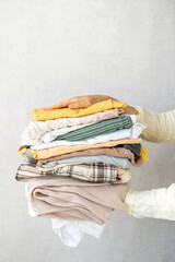 Laundry, woman holds stack of clothes in her hands after dry cleaning. housework, cleaning and...