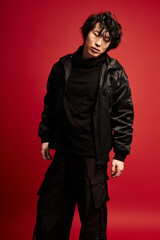 Dashing korean model strikes a confident pose in a studio setting with a bold backdrop