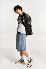 Naklejka premium Asian man's modern pose echoes timeless style in studio lighting
