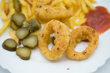 Platter with calamari and fries, tomato paste, pickled cucumbers in Transylvania,
