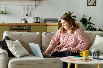 Young woman with Down syndrome enjoys a cozy moment at home while using her laptop