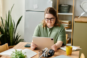Young woman with Down syndrome enjoys a cozy moment at home while using a tablet