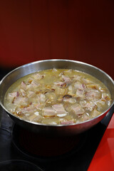 trozos de panceta friéndose en una sartén en los fogones de la cocina 