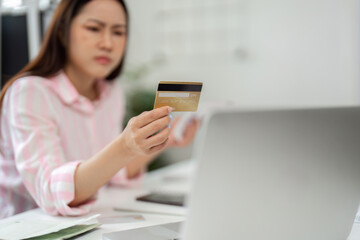 Financial Management and Decision Making. A woman examines her credit card while working from home.