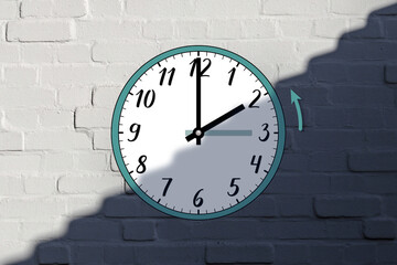 The clock shows its hands moving back from 3 a.m. to 2 a.m. in autumn. The end of daylight saving time. The time transition. Against a white brick wall, divided in half by a shadow.