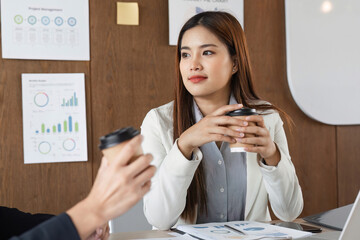 Business Discussion and Collaboration. A professional woman engages in a constructive conversation over coffee with a colleague in a modern office setting.