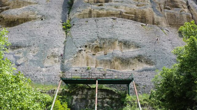 Pedestal drone shot in front of a scaffolding erected by the rock cliff side of Madara Plateau showing the Madara Horseman bas relief in a historical site in Bulgaria.
