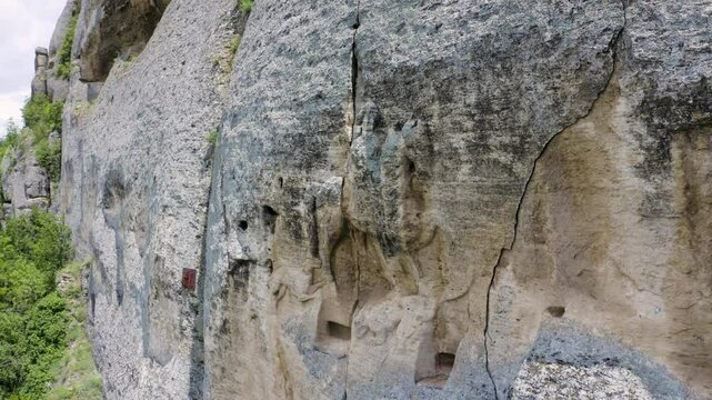 Drone panning from the right to the left showing a natural rock formation wall of the Madara Plateau near Shumen where the Madara Rider or locally known as Madarski Konnik in Bulgaria.