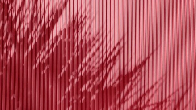 Shadow of palm leaves on vertical red corrugated metal wall. Abstract natural light and line pattern background. Design for wallpaper, banner, postcard, greeting card, poster, vertical