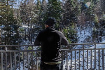 Man Overlooking Snowy Forest from Balcony